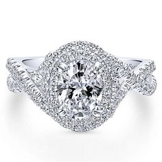 a white gold engagement ring with an oval center surrounded by round diamonds