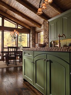 a large kitchen with green cabinets and wood flooring, along with a dining room table