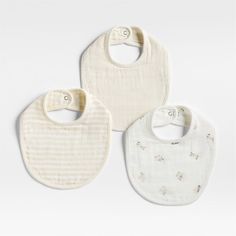 three bibs with white and beige designs on them