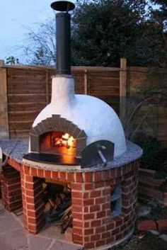 an outdoor brick pizza oven in the middle of a yard with firewood and bricks surrounding it