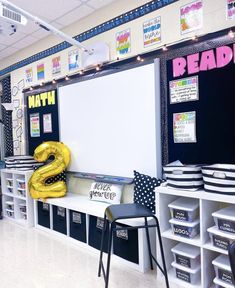 a classroom with whiteboard, black and white bins, yellow balloon shaped like the number two