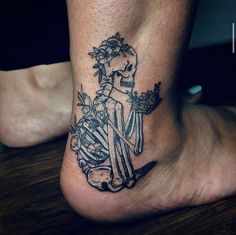 a woman's foot with a skeleton and flowers tattoo on the bottom of it