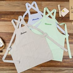 three personalized aprons sitting on top of a wooden floor next to a pair of shoes