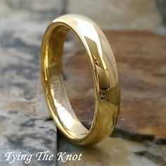 a gold wedding ring sitting on top of a stone floor