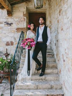 a man and woman standing on the steps of a building with flowers in their hair