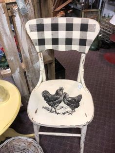 an old chair with two chickens painted on the back and seat is sitting next to a basket