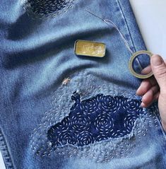 someone is stitching the holes in their jeans