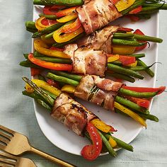 a white plate topped with chicken and veggies covered in kebabs on skewers