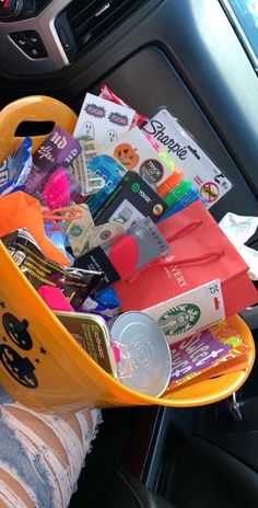 a person holding a yellow basket filled with items in their car's dash board