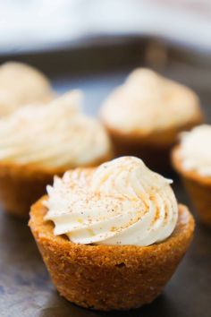 several cupcakes with white frosting sitting on a tray