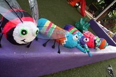 a group of stuffed bugs sitting on top of a purple table covered in fake grass