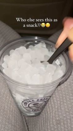 a person holding a plastic cup filled with ice cubes