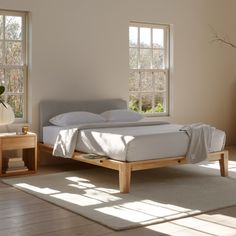 a bed sitting on top of a wooden frame in a bedroom next to two windows