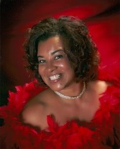 a woman in a red feathered dress smiling at the camera