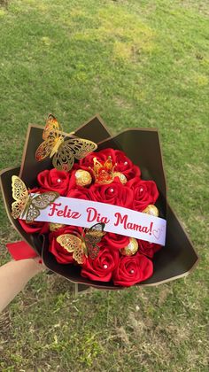 a bouquet of red roses and butterflies in a cardboard box with a ribbon that says feliz diy mama