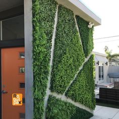 a house with a green wall and orange door in front of the entrance to it