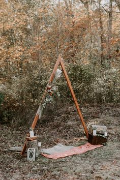 a teepee in the middle of a forest with flowers and candles on top of it