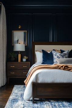 a bed with blue and white pillows in a dark room next to a wooden dresser