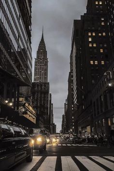 cars are driving down the street in front of tall buildings at night with lights on