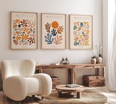 three framed art prints hang on the wall above a white chair in a living room