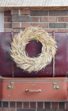 a suitcase with a wreath on top of it sitting next to a brick wall and door