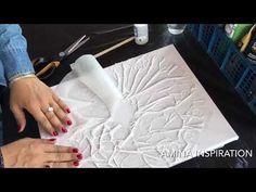 a woman is working on an art project with white paper and scissors, while another person holds