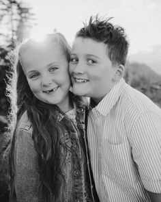 two young children are posing for a black and white photo with trees in the background