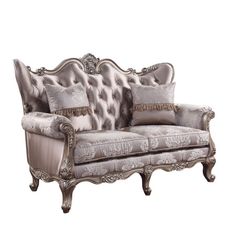 an ornate couch with pillows on it and silver trimmings, sitting against a white background