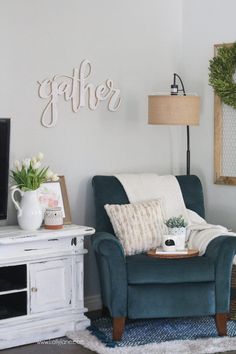 a living room with a blue chair and a white coffee table in front of a tv