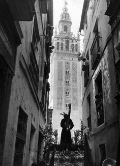 an old photo of a man walking down the street in front of a tall building