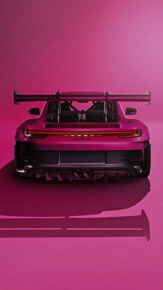 the back end of a red sports car with its hood up on a pink background