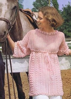 a woman standing next to a horse in front of a fence with her hand on the bridle