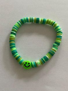 Colourful bracelet in shades of green with a smiley face Fun Green Round Jewelry, Adjustable Green Beaded Bracelets For Friendship, Playful Green Round Jewelry, Green Round Beads Friendship Bracelet, Handmade Green Playful Friendship Bracelets, Playful Handmade Green Friendship Bracelets, Fun Green Handmade Beaded Bracelets, Green Beaded Friendship Bracelets, Green Beaded Bracelets For Friendship