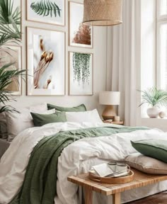 a bedroom with white walls and green bedding, pictures on the wall above the bed