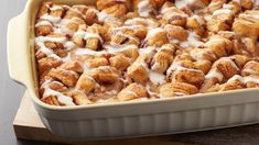 a casserole dish filled with cinnamon rolls covered in icing and drizzle