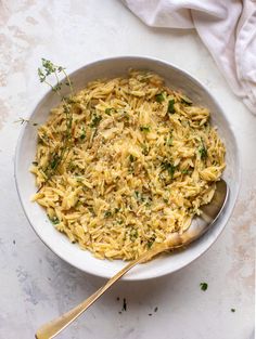 a white bowl filled with pasta and parsley on top of a marble countertop