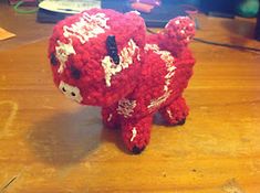 a red stuffed animal sitting on top of a wooden table