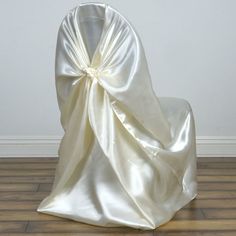 the back of a chair covered in a white satin fabric with a bow on it