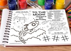 a coloring book with space and rockets on it, surrounded by crayon markers