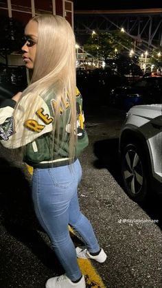 a woman with long blonde hair standing next to a car