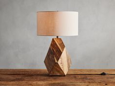 a wooden table lamp sitting on top of a wooden table next to a white lampshade