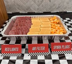 an assortment of different types of food in trays on a checkered tablecloth