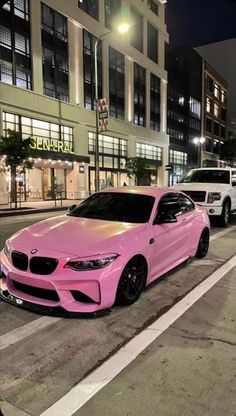 two pink cars are parked on the side of the road in front of a building