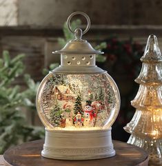 a snow globe sitting on top of a table next to a christmas tree and other decorations