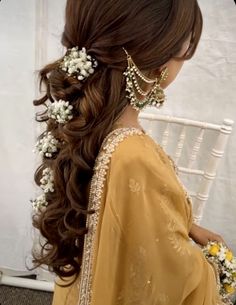 a woman with long hair and flowers in her hair is sitting on a white chair