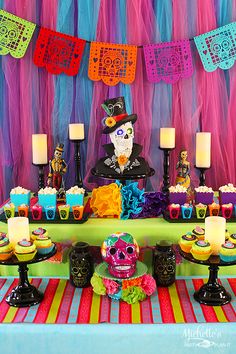 a table topped with cupcakes and cakes covered in frosting next to candles