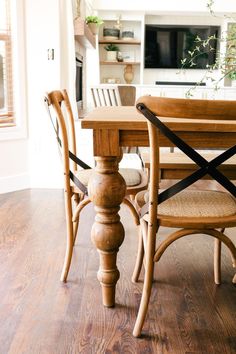 a wooden table and chairs in a room with hardwood floors, white walls and windows