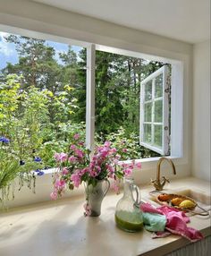 a kitchen counter with flowers in vases on it and an open window to the outside