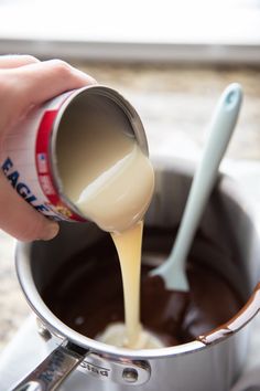 a person pouring melted chocolate into a saucepan