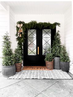 the front door is decorated for christmas with greenery and potted trees